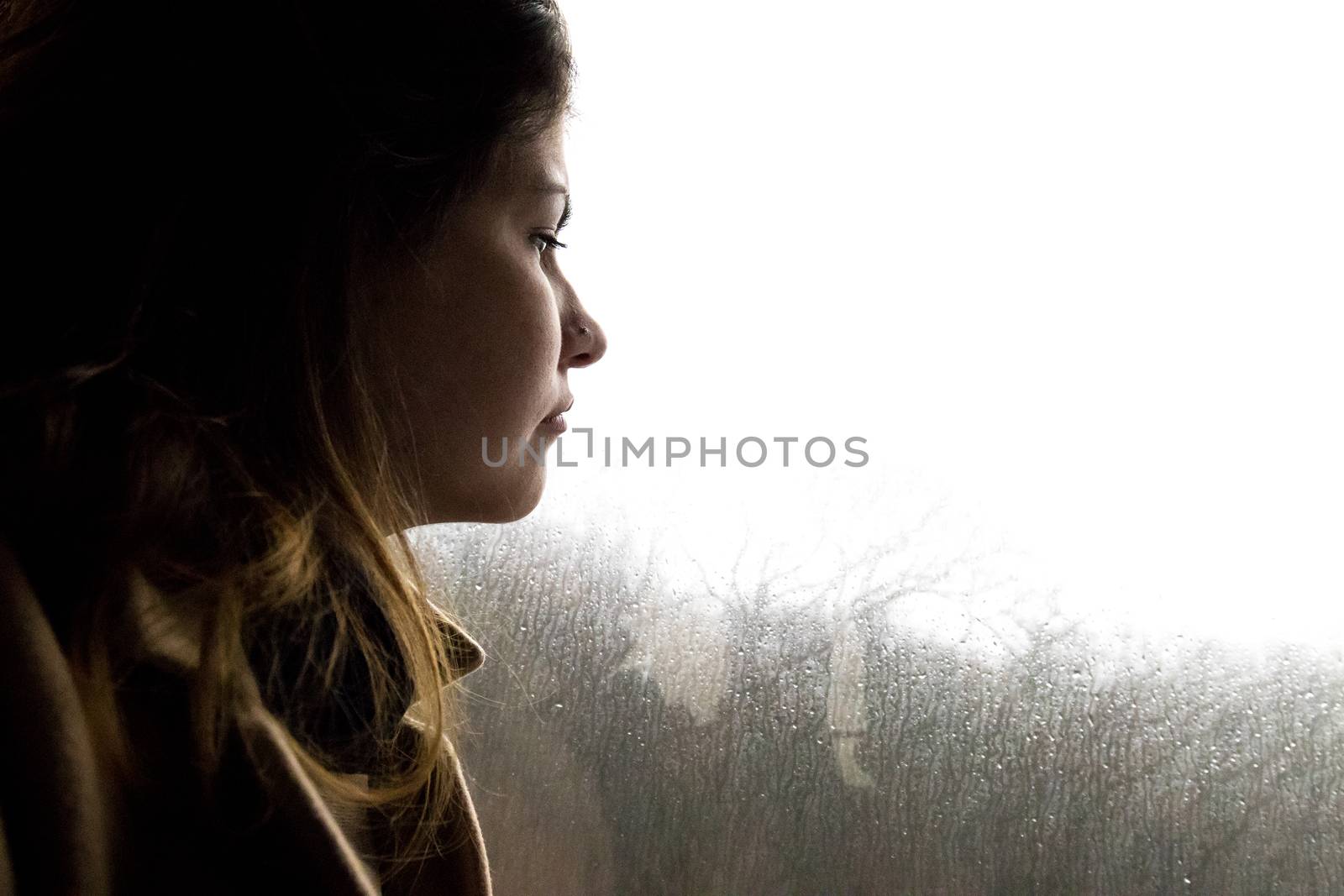Beautifull girl looking at the bus window while is raining outside. 