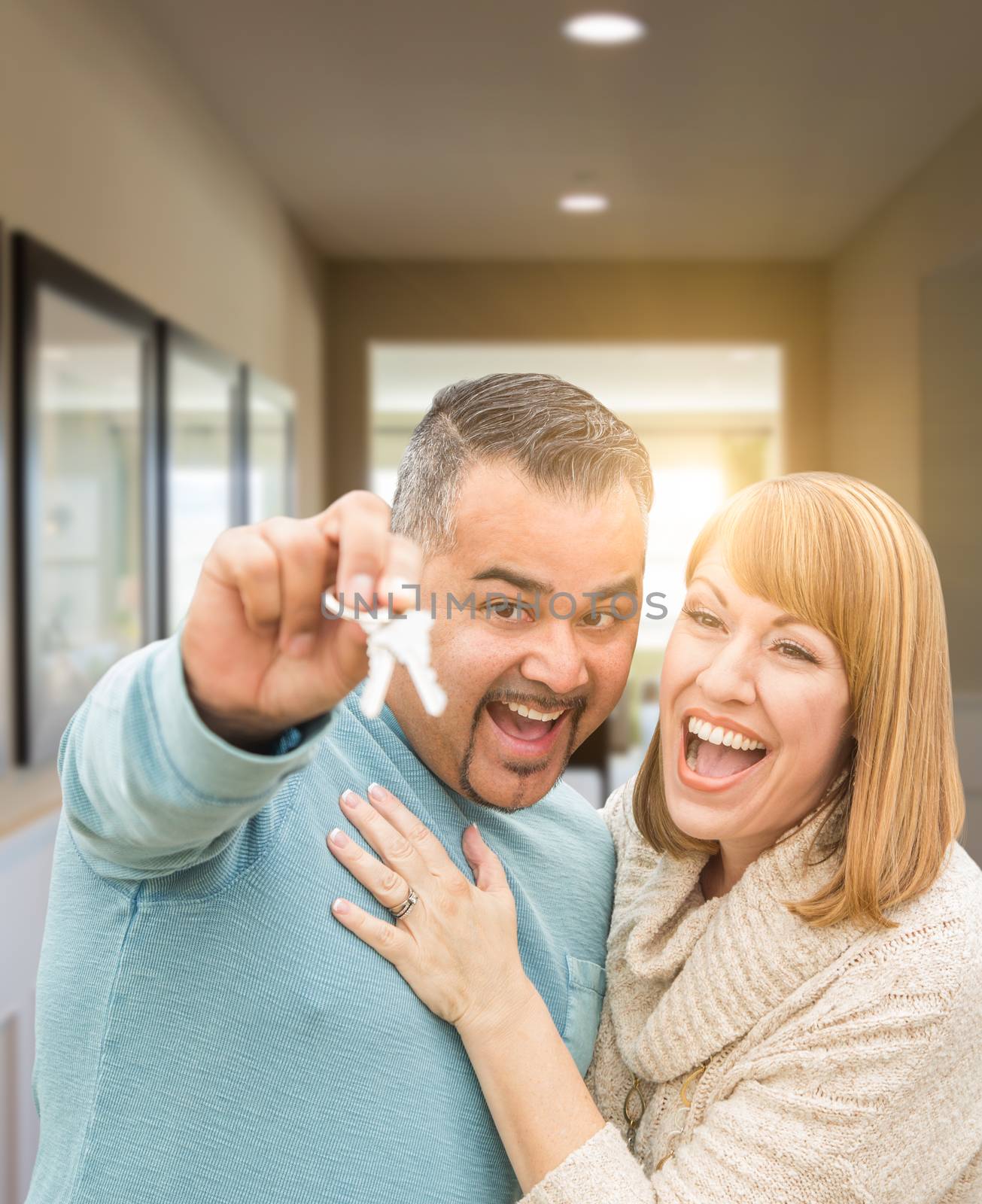 Couple Holding House Keys Inside Hallway of Their New Home by Feverpitched