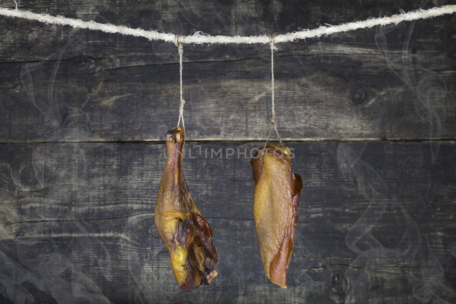 Smoked Chicken Meat Hanging on the Rope Against Wooden Background With Smoke