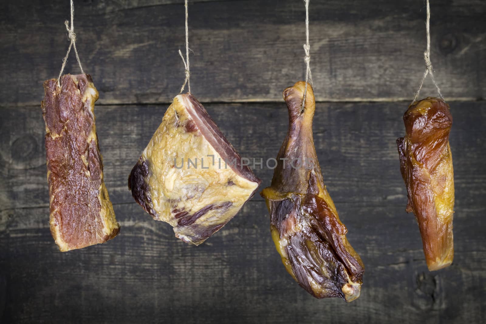 Smoked Pork and Chicken Meat Hanging on the Rope Against Wooden Background