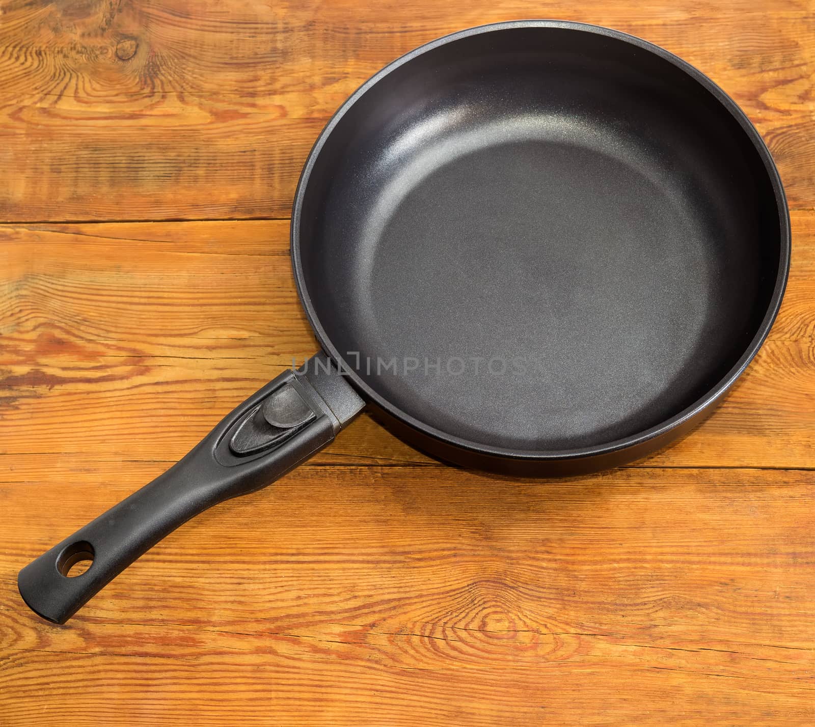 Frying pan with ceramic non-stick coating on wooden surface by anmbph