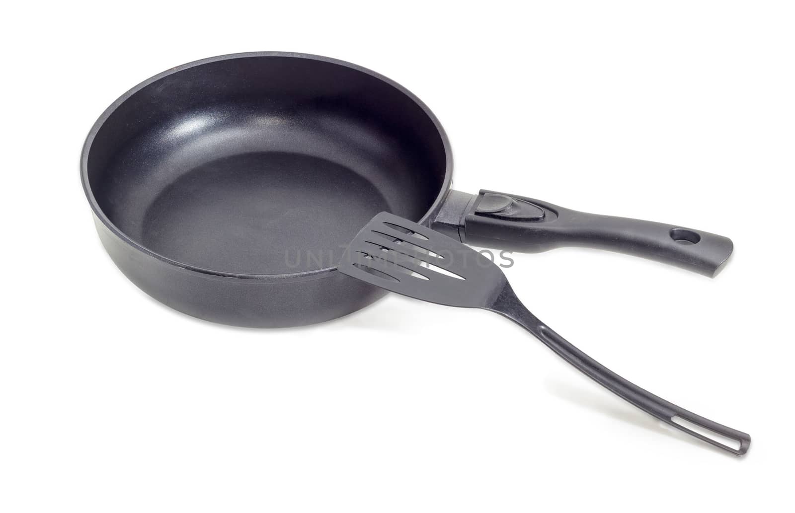 Cast frying pan, made of aluminium alloy with removable handle and plastic spatula on a light background
