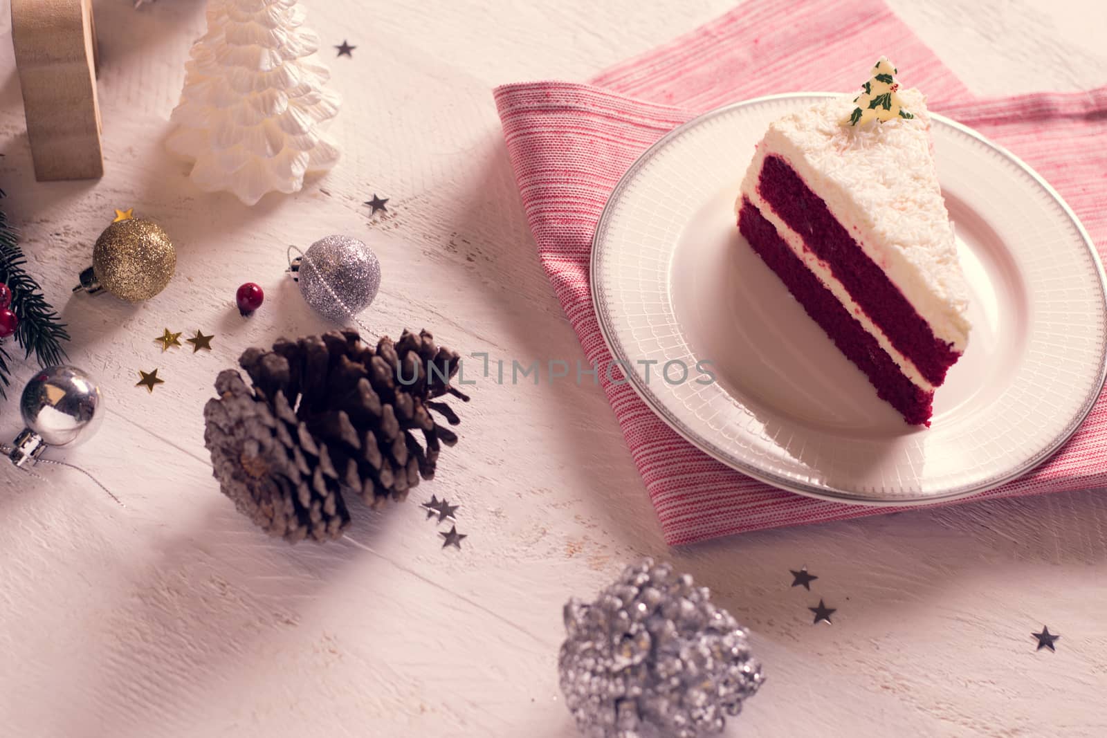 Christmas cake on plate on red fabric on wood background and decorations.