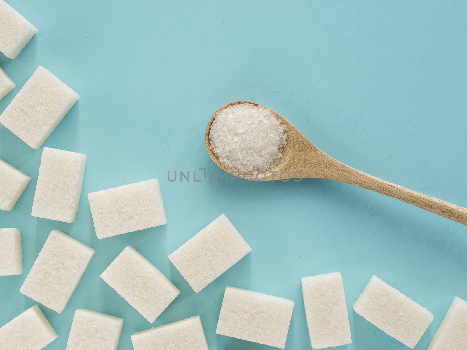 background of sugar cubes and sugar in spoon. White sugar on blue background. Sugar with copy space. Top view or flat lay