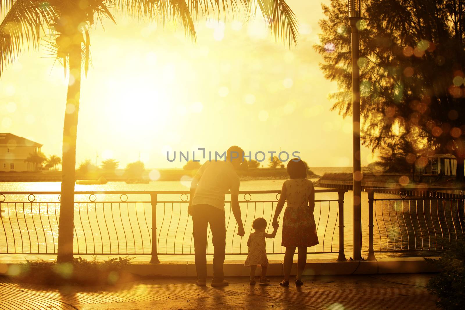 Rear view silhouette of young family enjoying outdoor activity together, walking in beautiful sunset during holiday vacation.