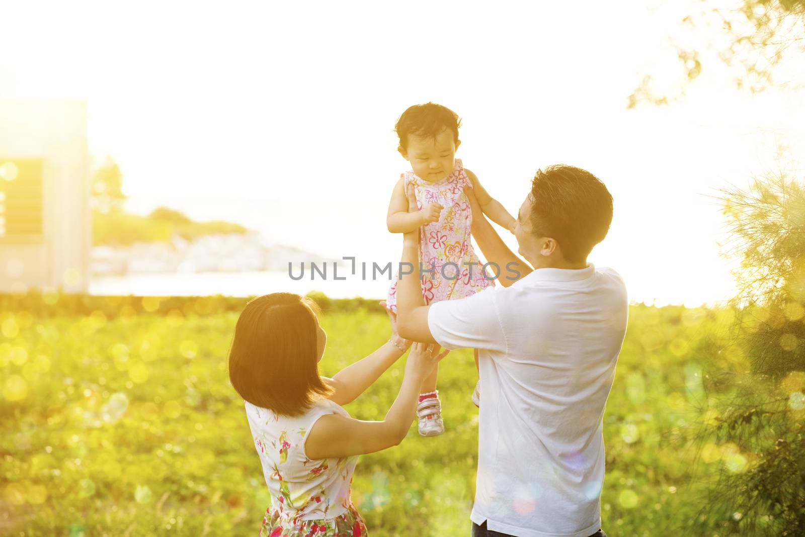 Portrait of lovely family enjoying outdoor activity together, walking on garden park in beautiful sunset during holiday vacations.