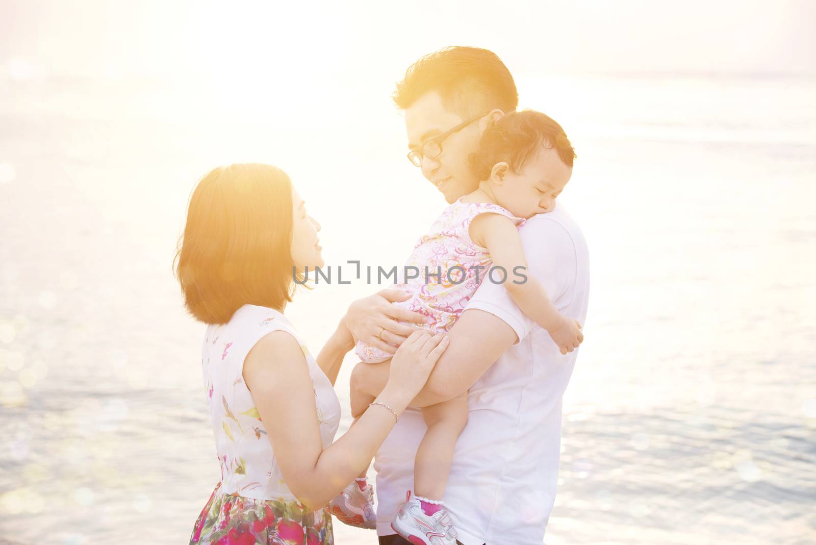 Happy Asian family outdoor portrait, enjoying holiday together on coastline in beautiful sunset during vacations.