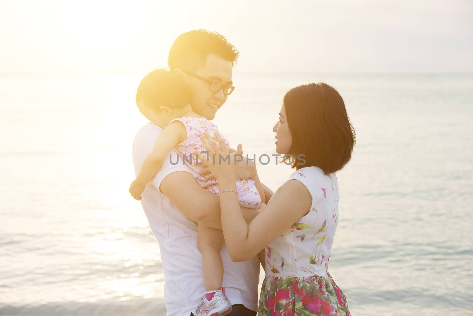 Asian family outdoor portrait, enjoying holiday together on coastline in beautiful sunset during vacations.