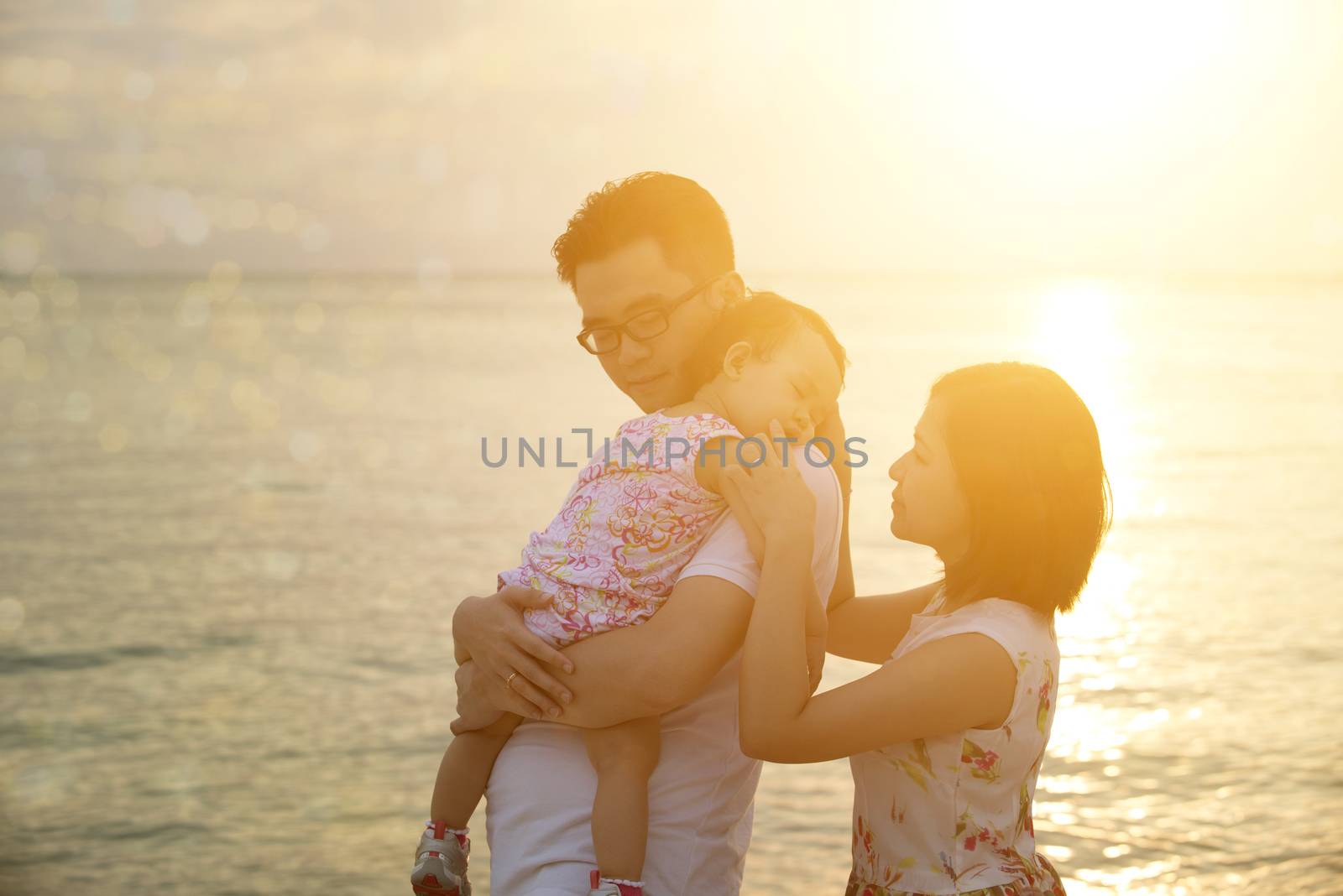 Silhouette of Asian family outdoor fun, enjoying holiday together on seaside in sunset during vacations.