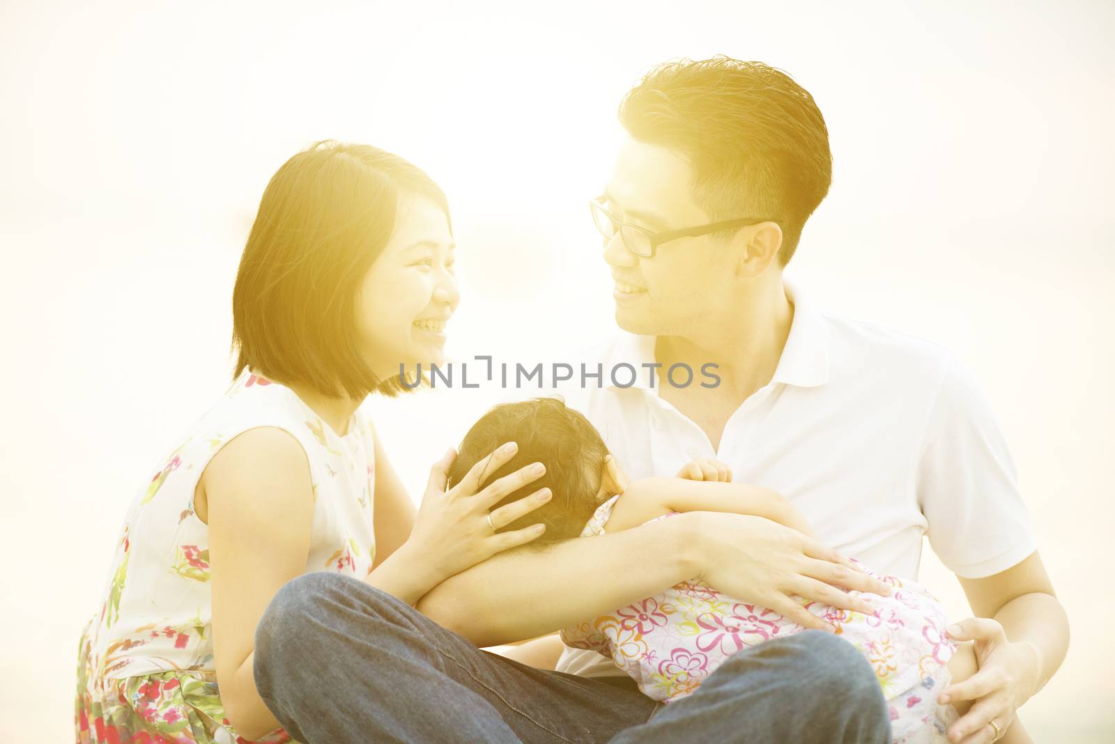 Happy Young Asian family outdoor portrait, having fun time together on beach in sunset during vacations.