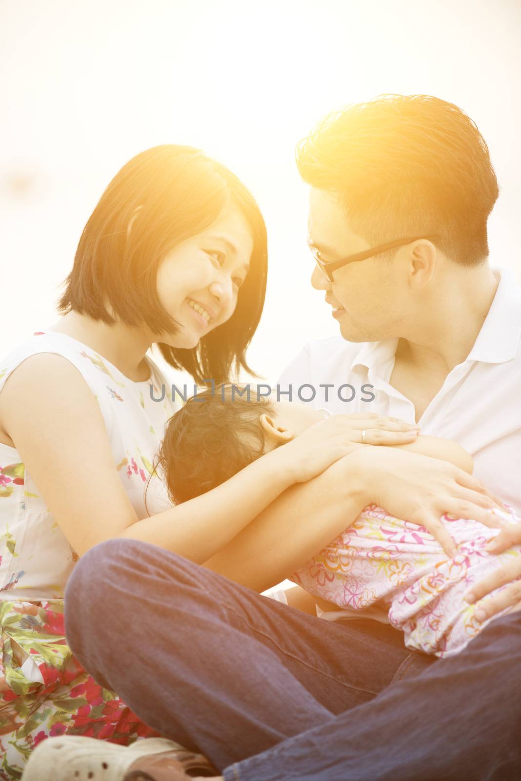 Happy Asian family outdoor portrait, having fun time together on beach in sunset during vacations.