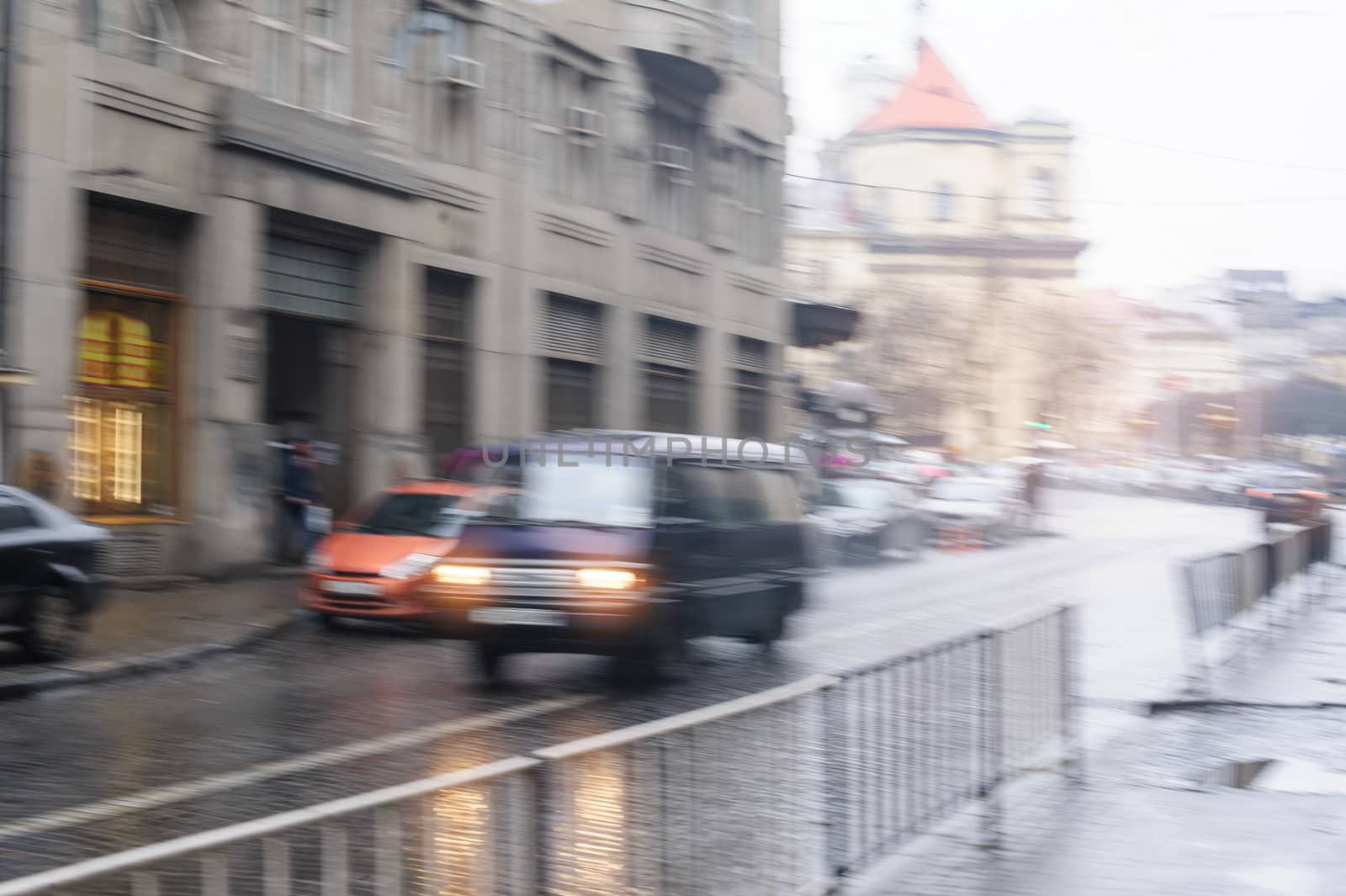 cars going down the street in the rain. blurred focus.