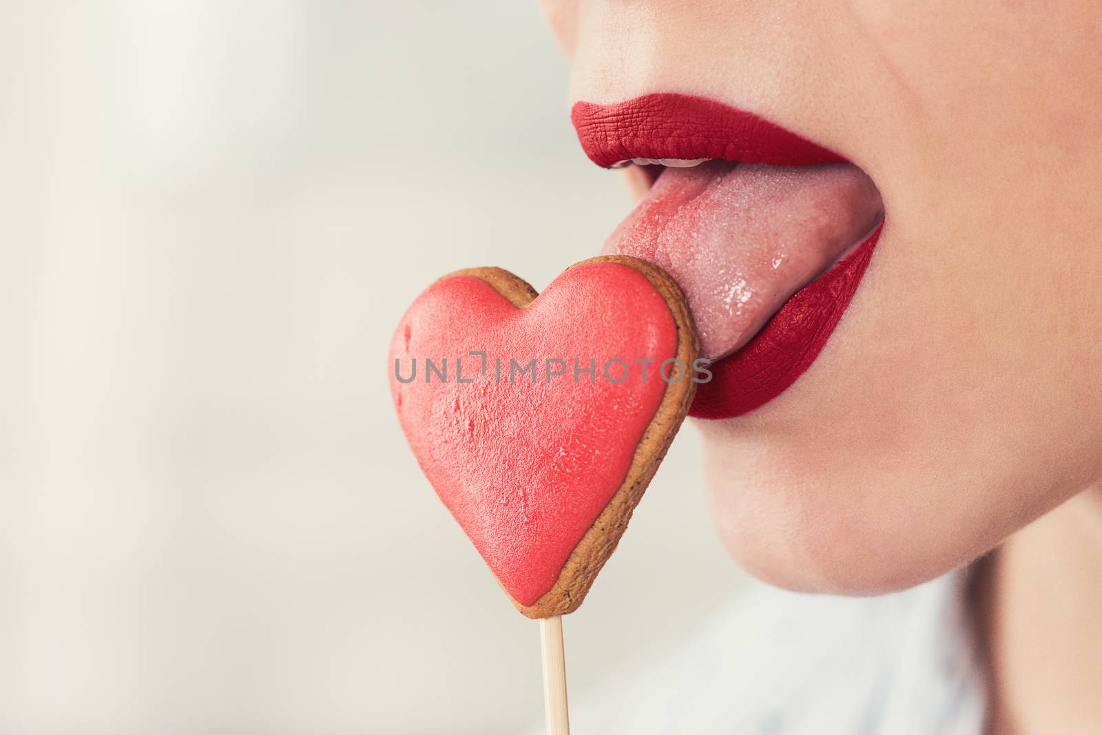 Closeup photo of the woman lips and gingerbread hearts on a stick, concept of love or valentines das