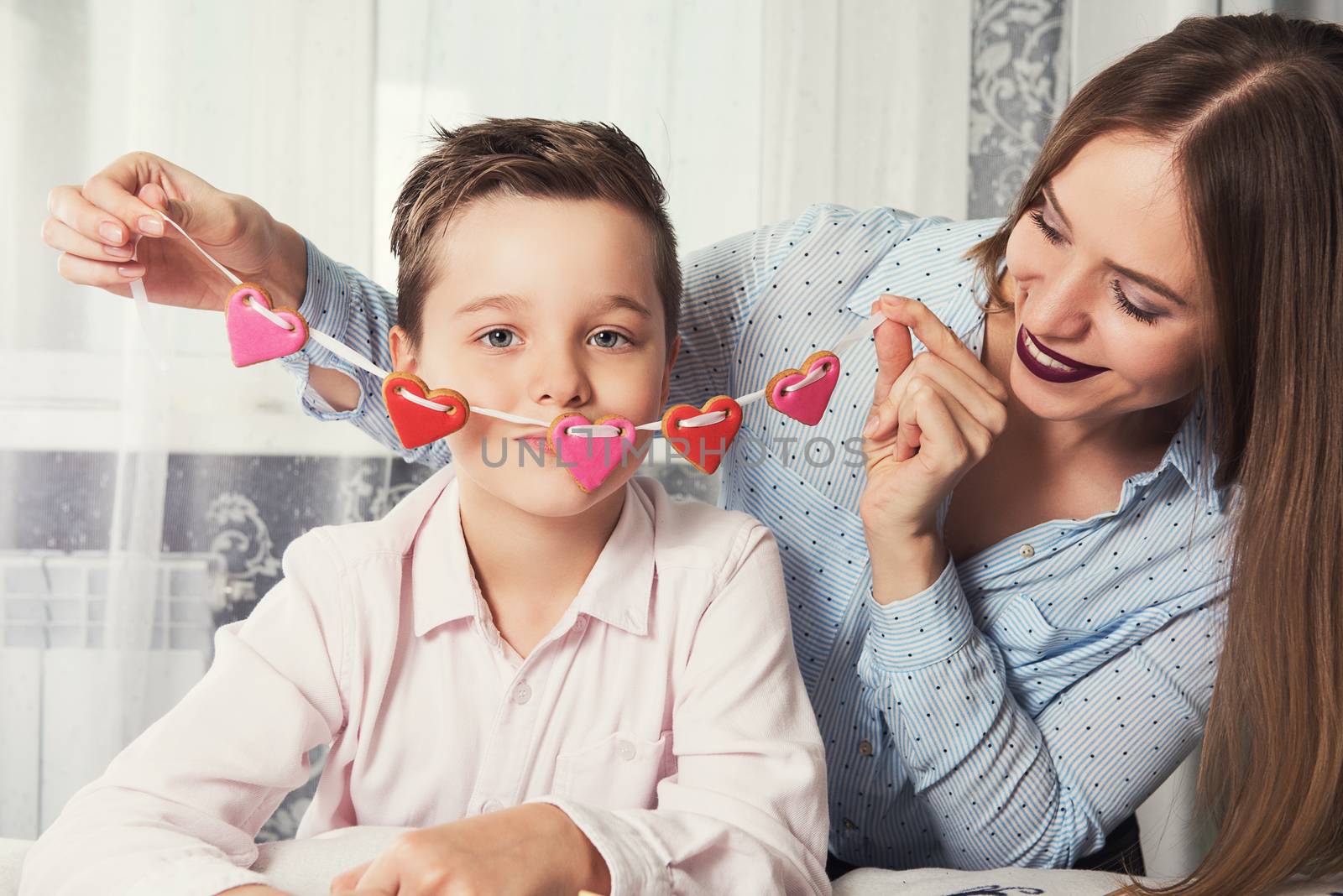 Happy Valentines Day or Mother day. Young boy and mum celebrate with gingerbread heart cookies on a stick.