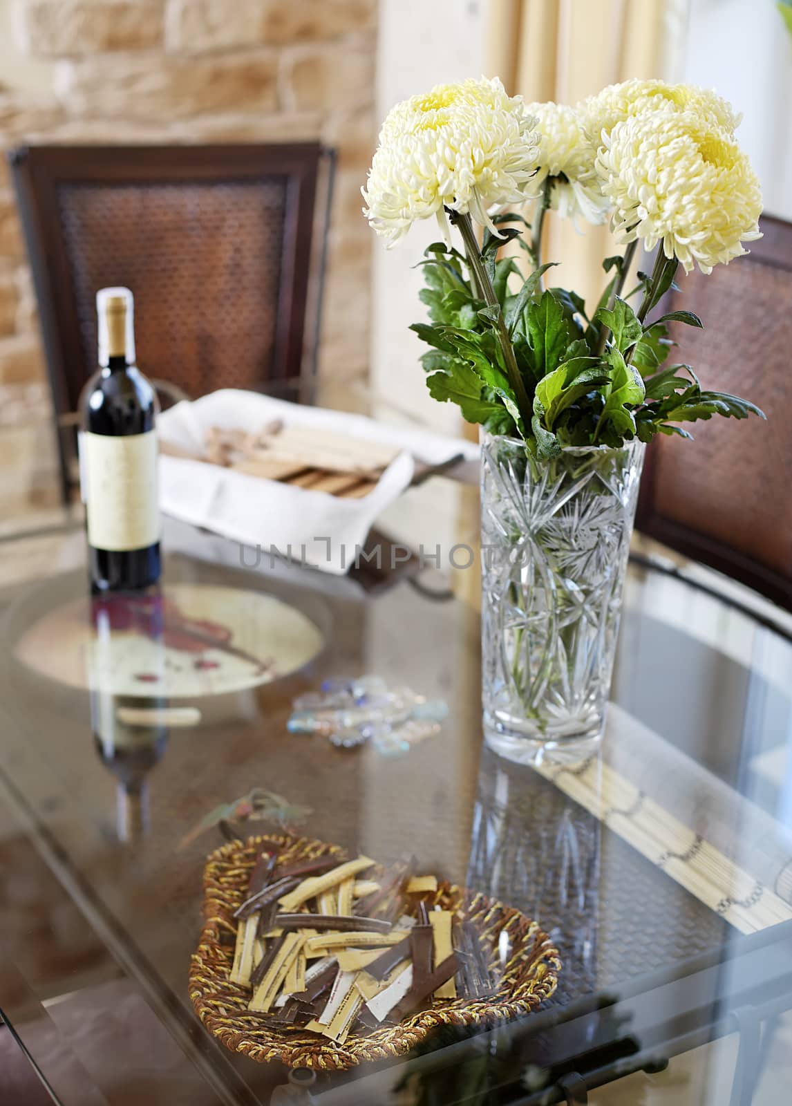 Beautiful vase with flowers and bottle of vine on glass diner ta by RawGroup