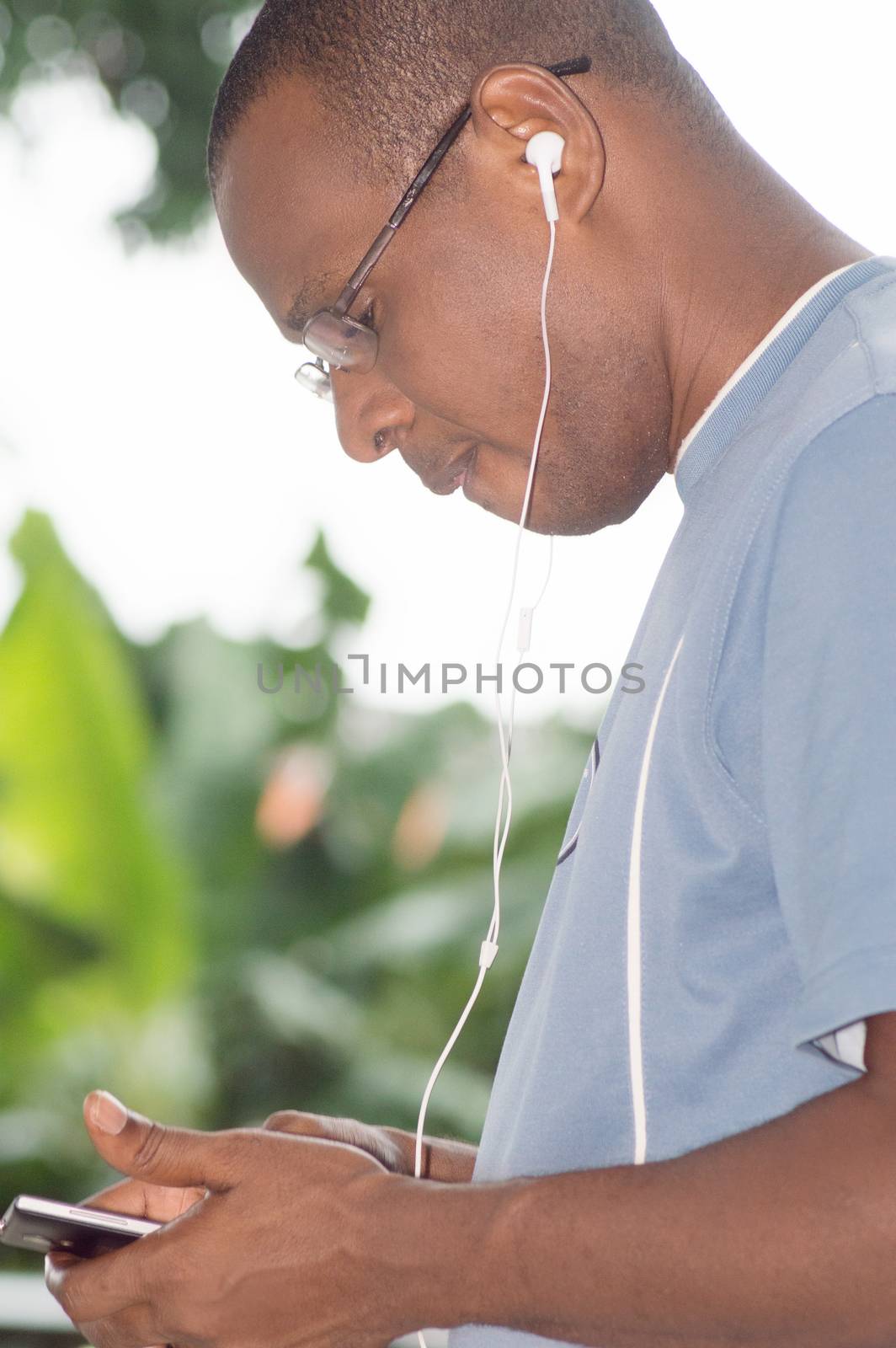 young man holding his mobile phone in hand and communicating with an earpiece.