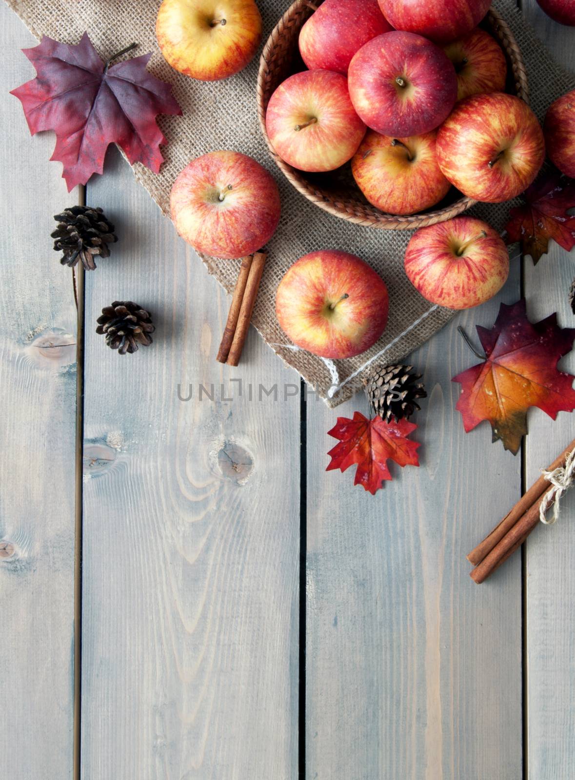 Autumn leaves with apples over a wooden background