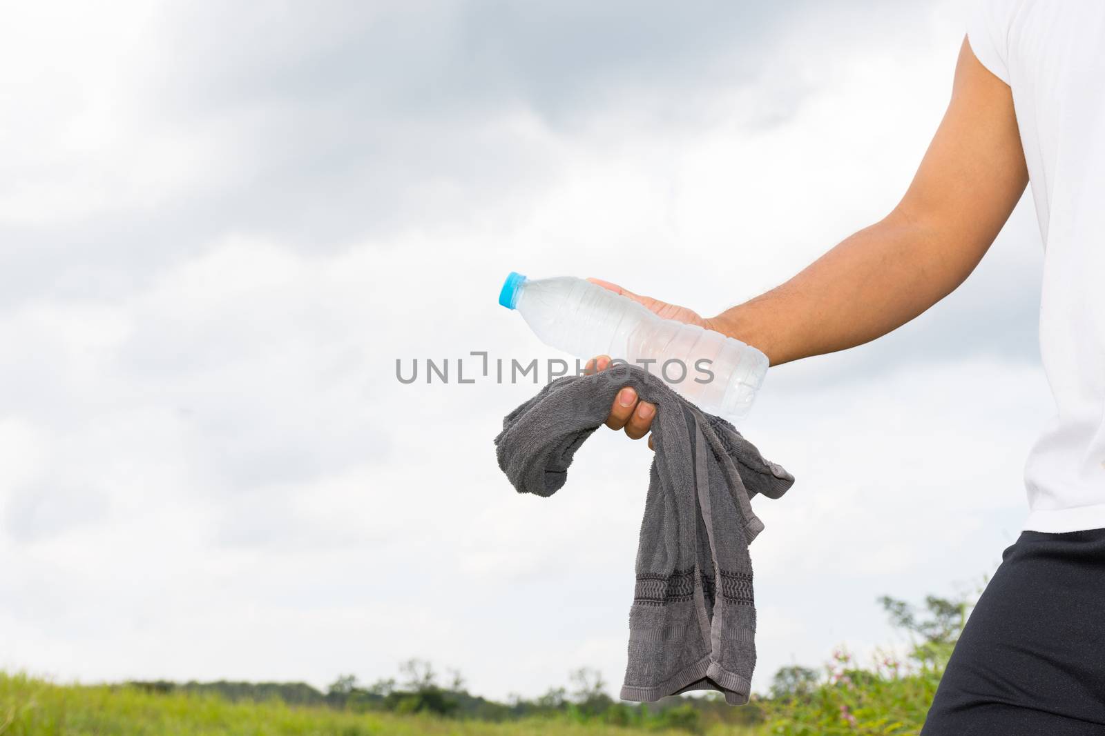 Man with water bottle and towel in his hand and nature background view.1