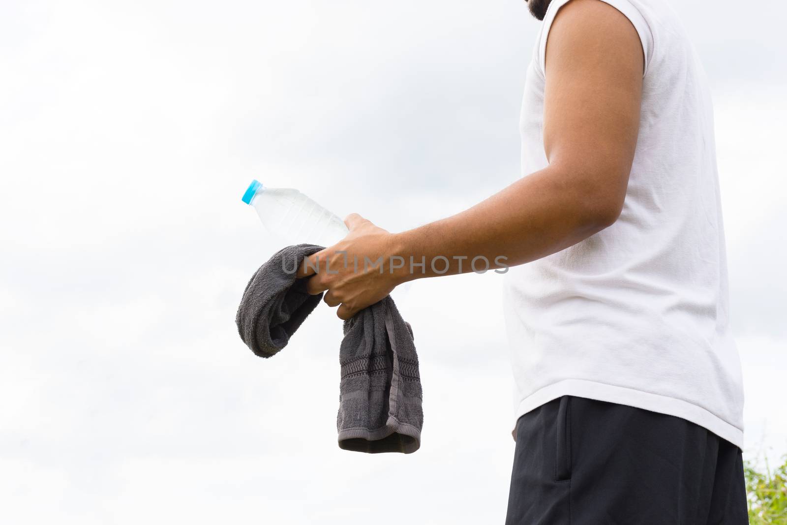 Man with water bottle and towel in his hand and nature background view.