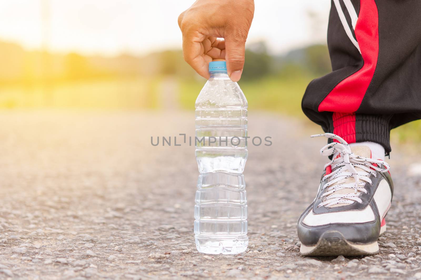 Sport man picked water bottle on the floor and background of mountain view.12 by engphoto