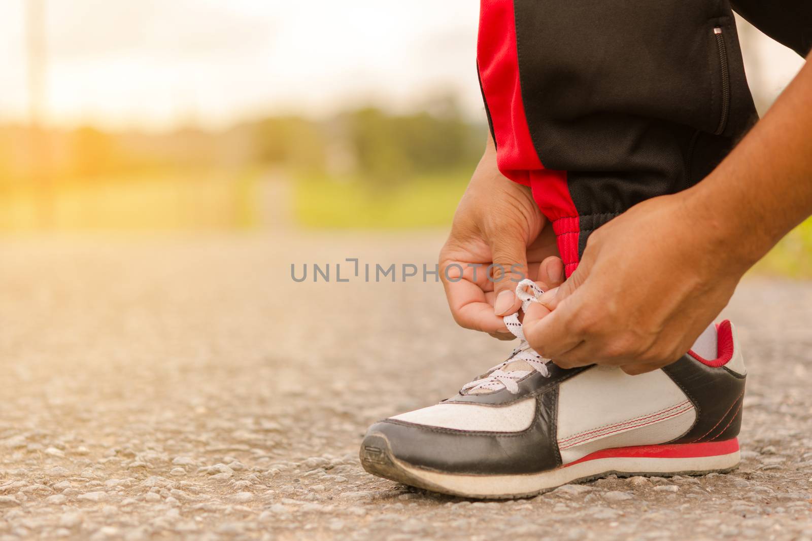 Man  tying shoes at roadside.Or sport man tying shoes. by engphoto