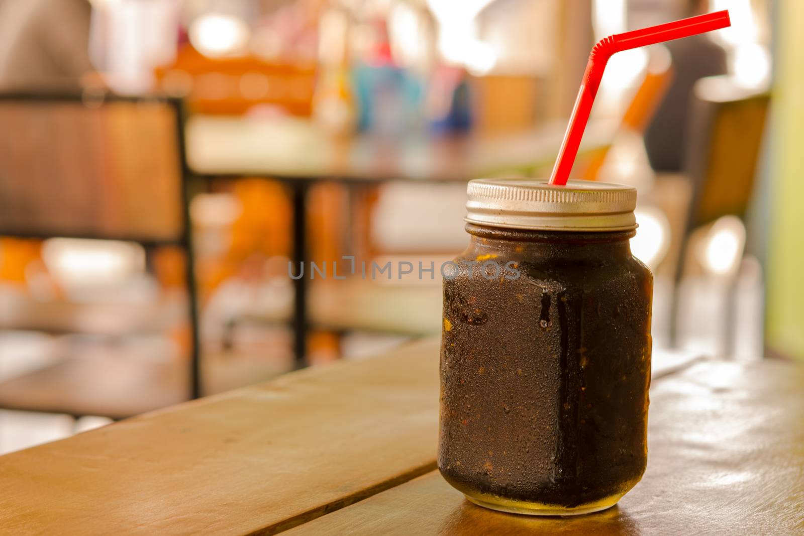 Black coffee in mason jar on table and background of restaurant in Asia. by engphoto