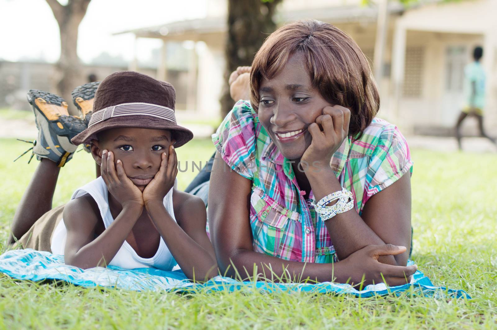 This young woman and her child are lying in the grass, mother smiling at her son.