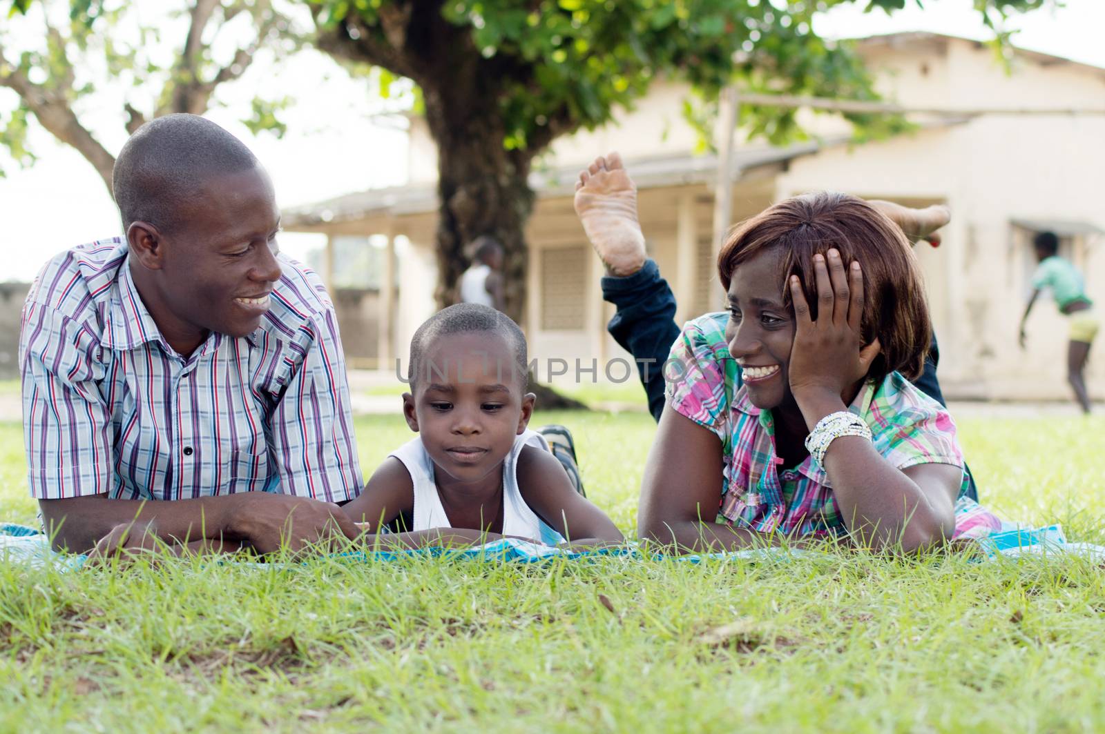 Young woman and her husband smiled , and their child lying in the middle of them.