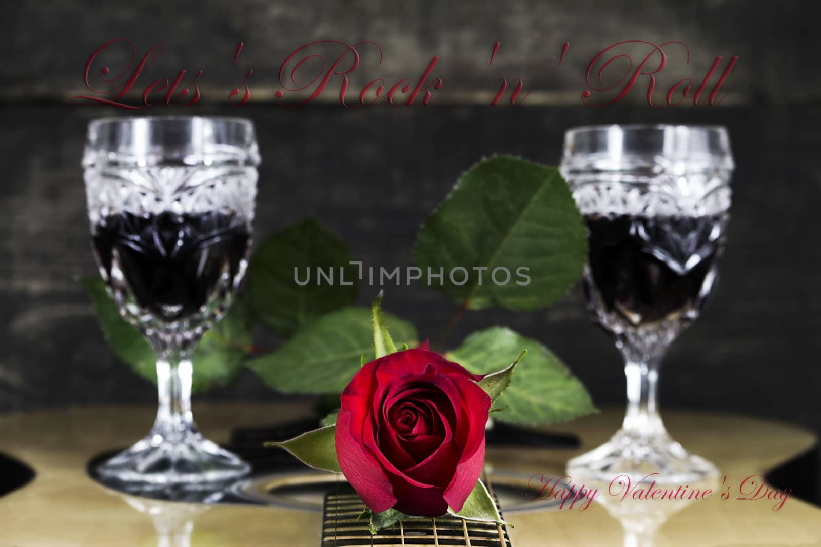 Red Rose and Wine Glasses Resting On Acoustic Guitar With Sign L by alexandarilich