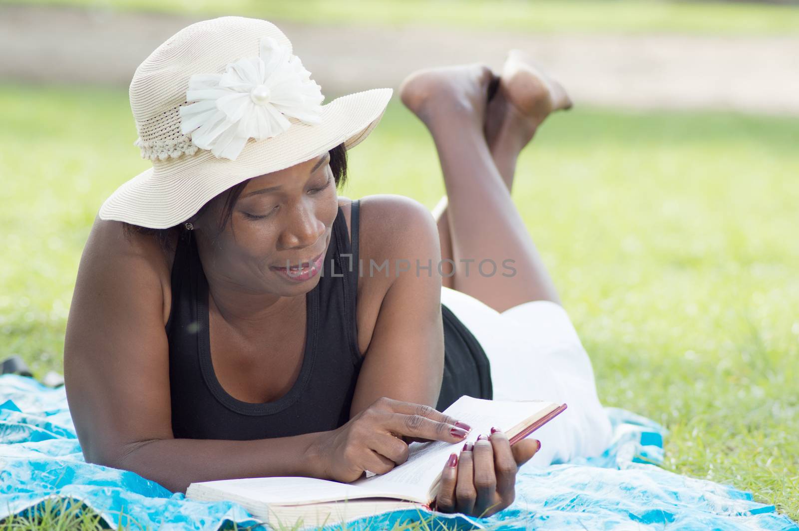 This young woman lying in the shade of a tree is reading quietly.