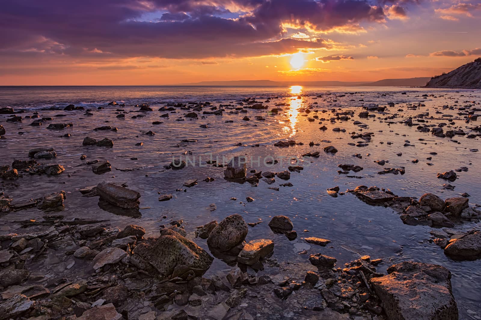 Exciting  rocky coast sunset with water reflection