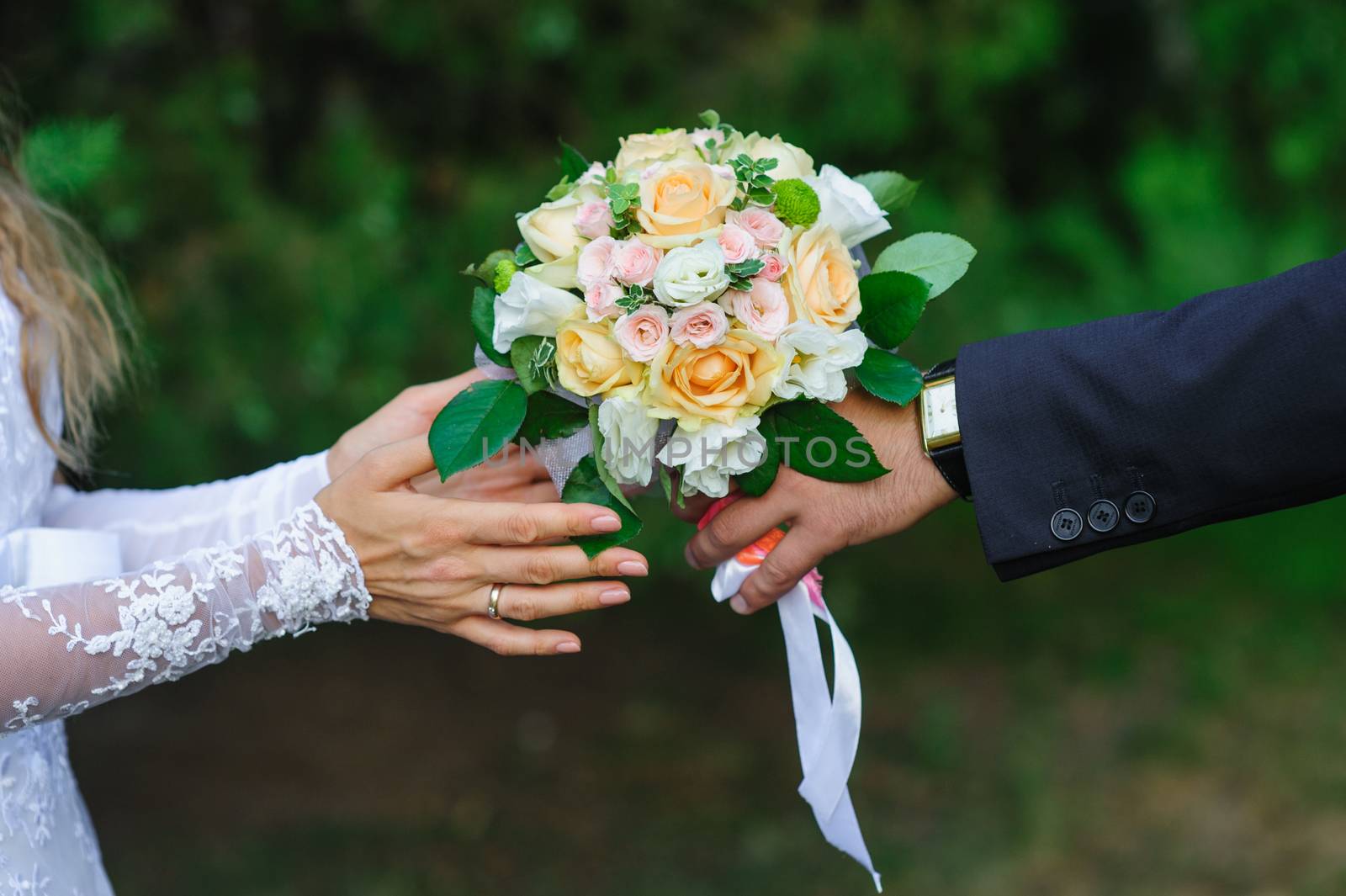 Groom gives bride a wedding bouquet in summer park by timonko