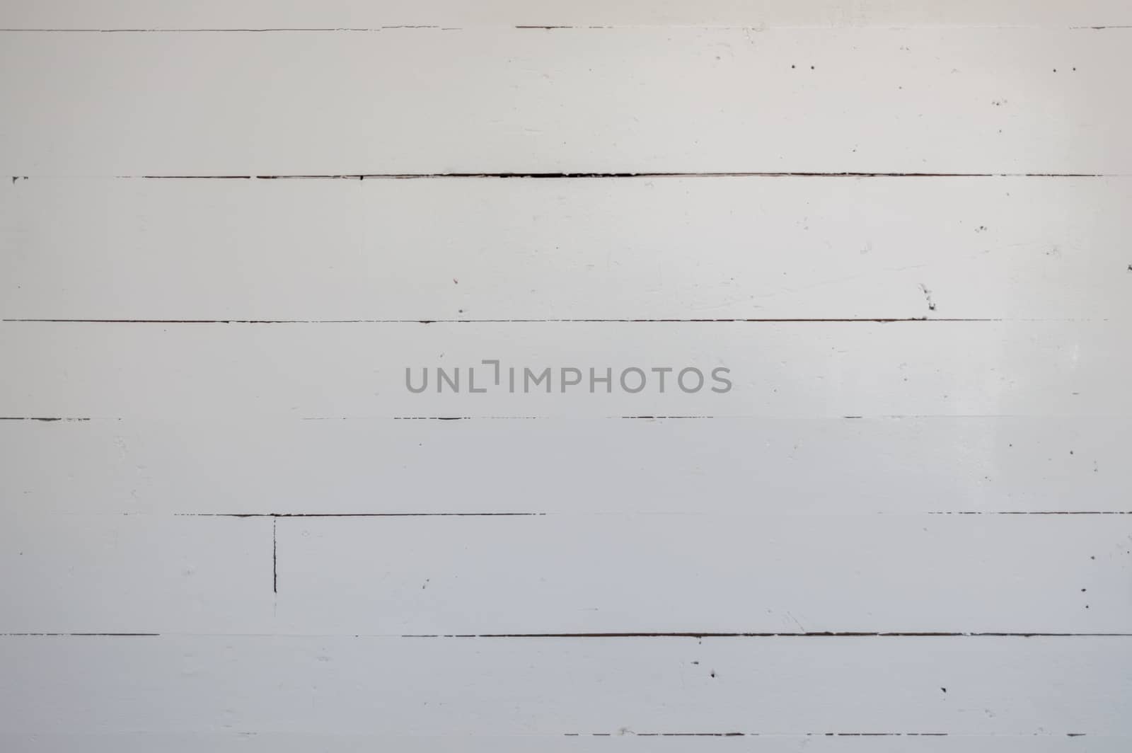 7 or 8 antique wooden boards run horizontally in an old farm house.  They are rustic and painted white.