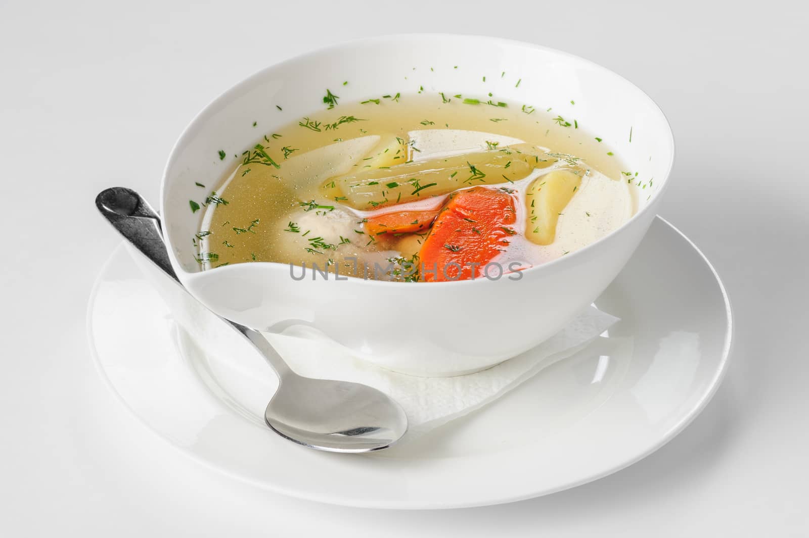 Clear soup with turkey meatballs, potatoes and other vegetables, served in white bowl