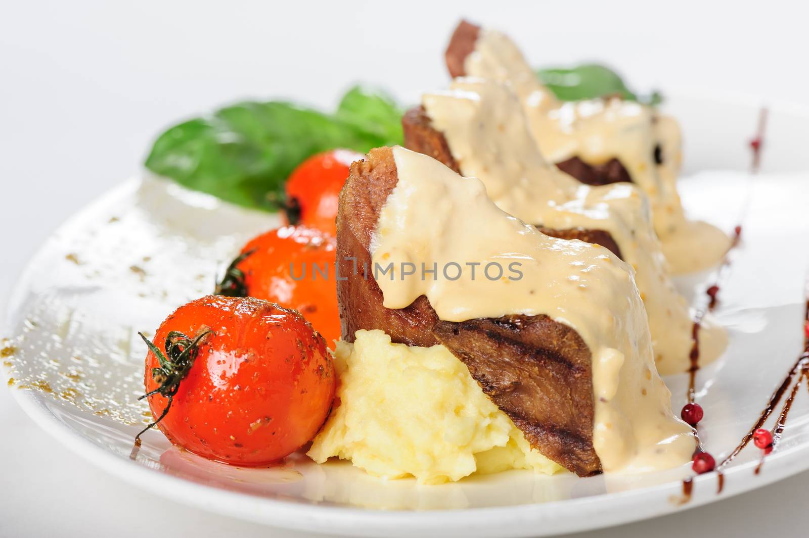 Baked mutton meat with creamy sauce, mashed potato and grilled cherry tomatoes, close up