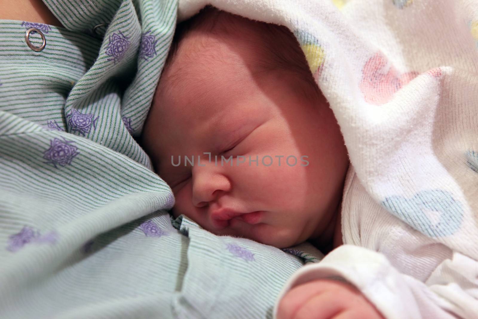 Sleeping newborn baby in the arms of my mother in hospital