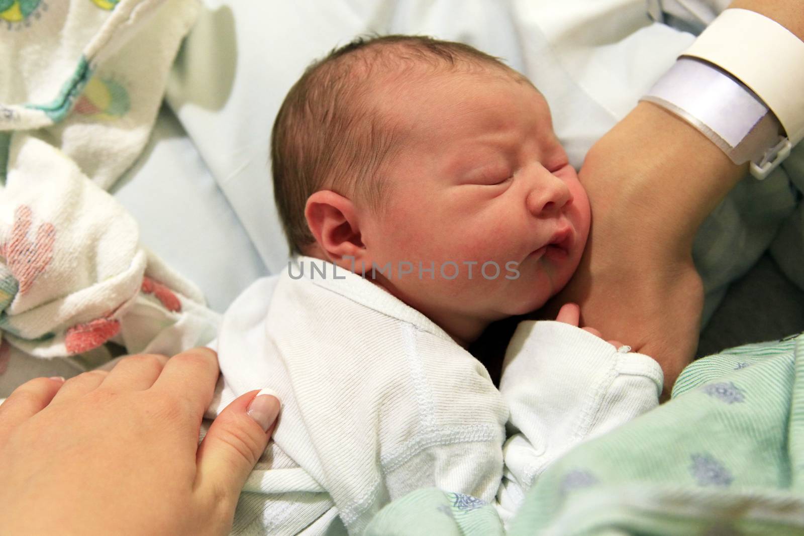 Sleeping newborn baby in the arms of my mother in hospital