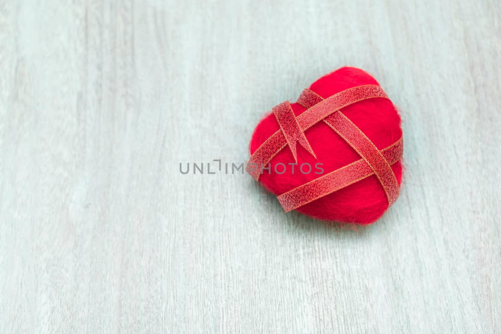 Ribbon wrapped heart on wood background