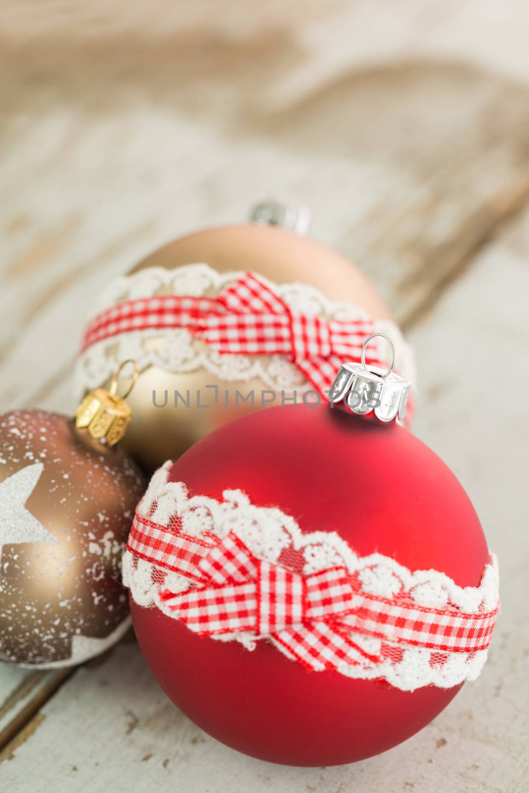 Three colorful decorated Christmas baubles on rustic wood with copy space to celebrate the Xmas holiday season