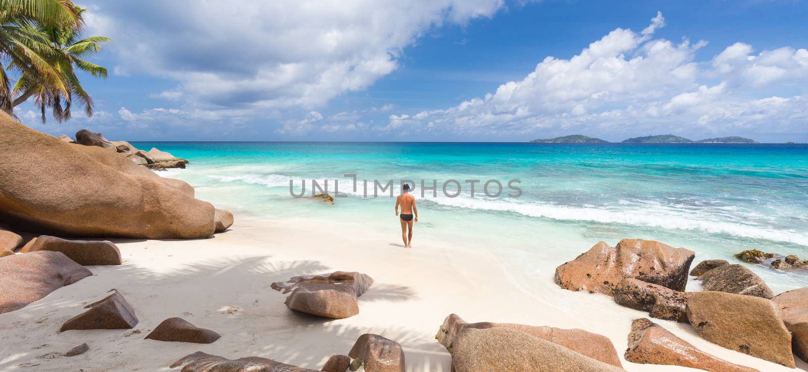 Man enjoying Anse Patates picture perfect beach on La Digue Island, Seychelles. by kasto