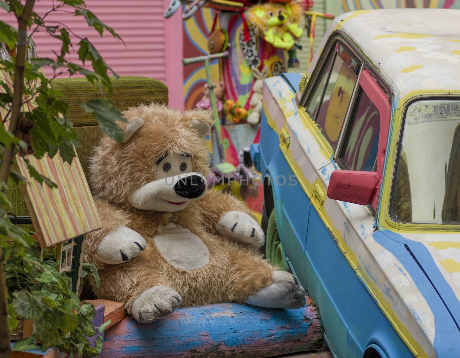 big teddy bear sits on a bench in the courtyard playground