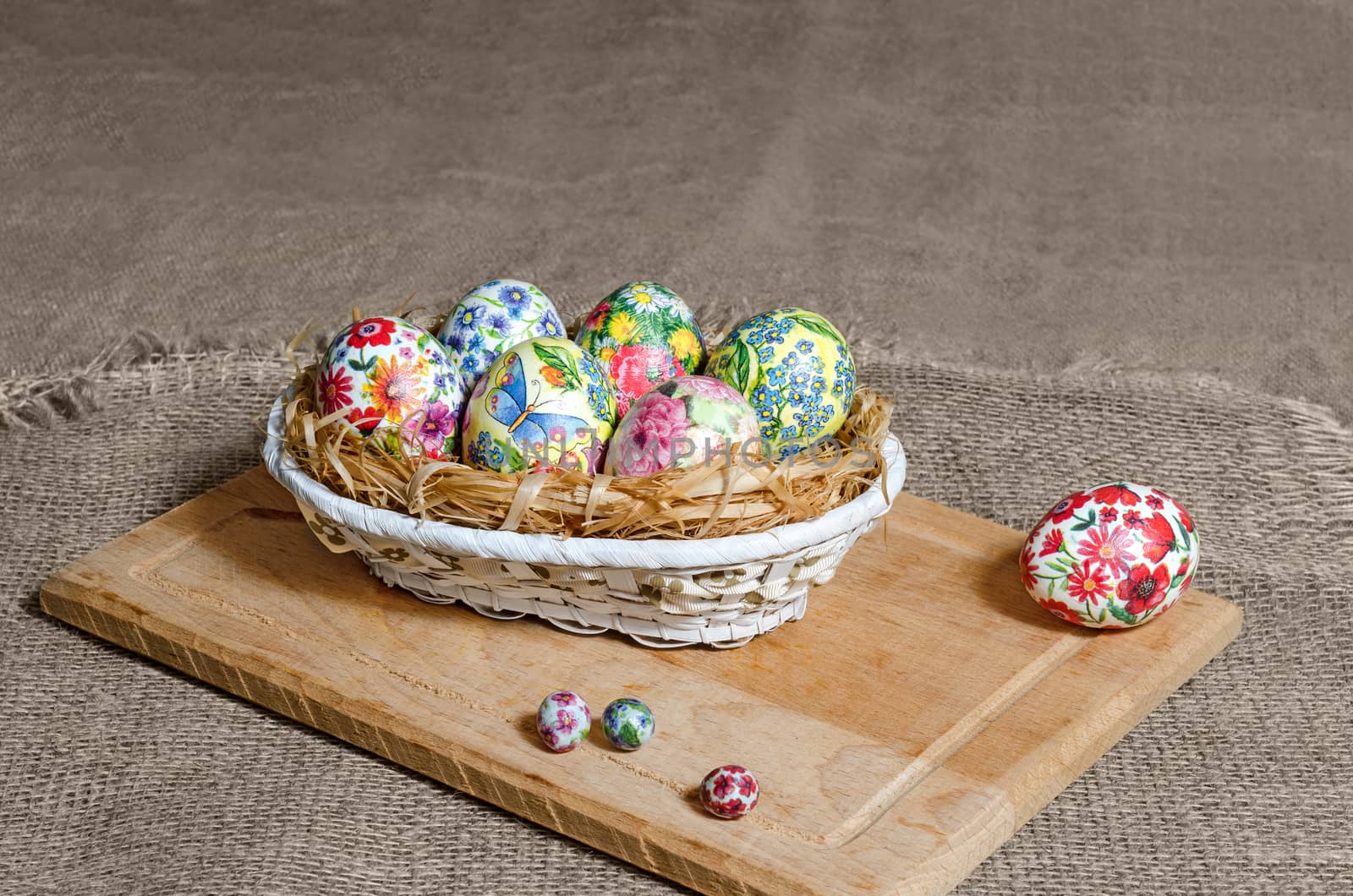 Decoupage Easter eggs are handmade in a wicker basket on the Board. Background of burlap, selective focus.