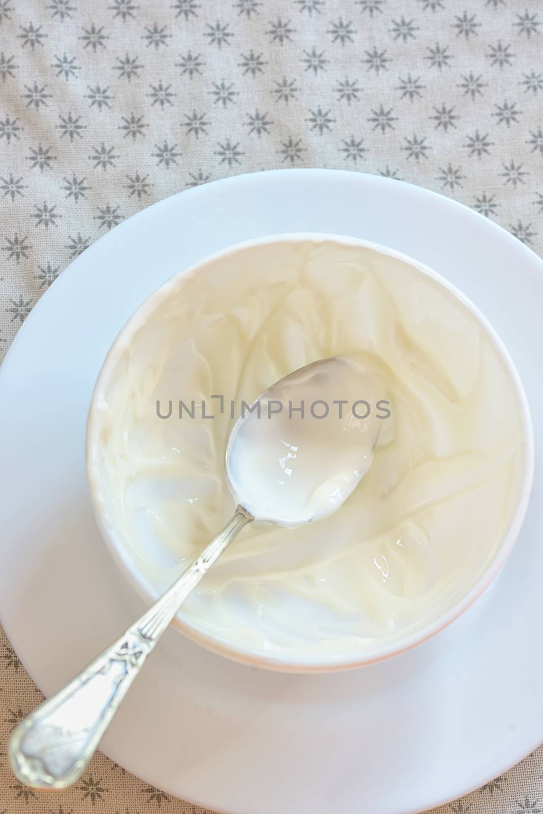 Emty ceramic bowl of white yoghurt and spoon