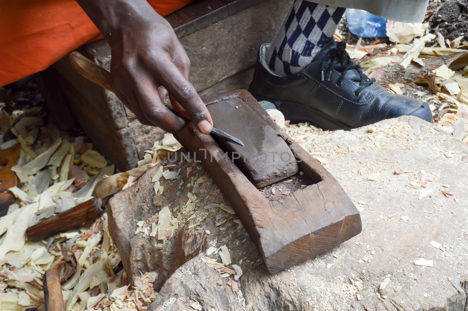 Kenyan sculptor sharpening a chisel on a pumice stone in a cooperative in Mombasa