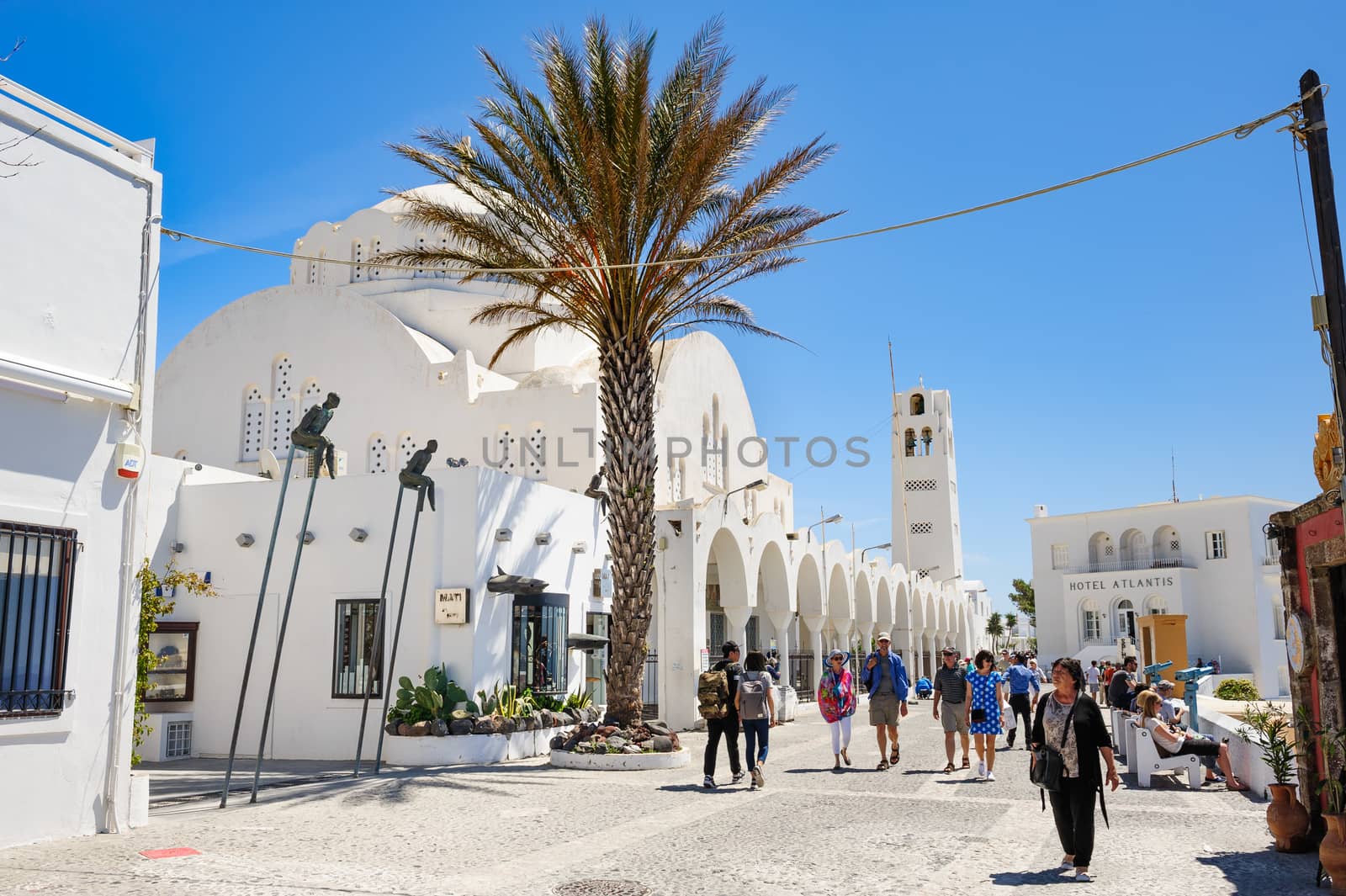 Fira, Santorini island, Greece - April 22nd, 2016: People walking at the central street of Fira. The Orthodox Cathedral, Church of Ipapanti, built in the 19th century sits prominently in the centre of Fira, the capital town of Santorini Island. Santorini is one of most famous greek resorts situated in Aegean sea at old volcano's caldera.