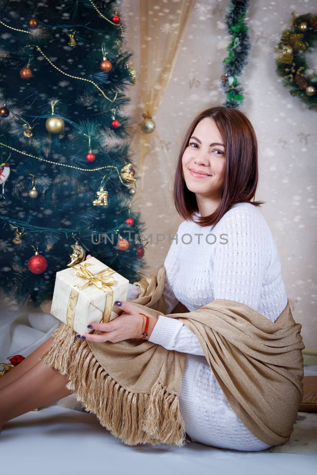 Pretty woman in golden shawl under Christmas tree