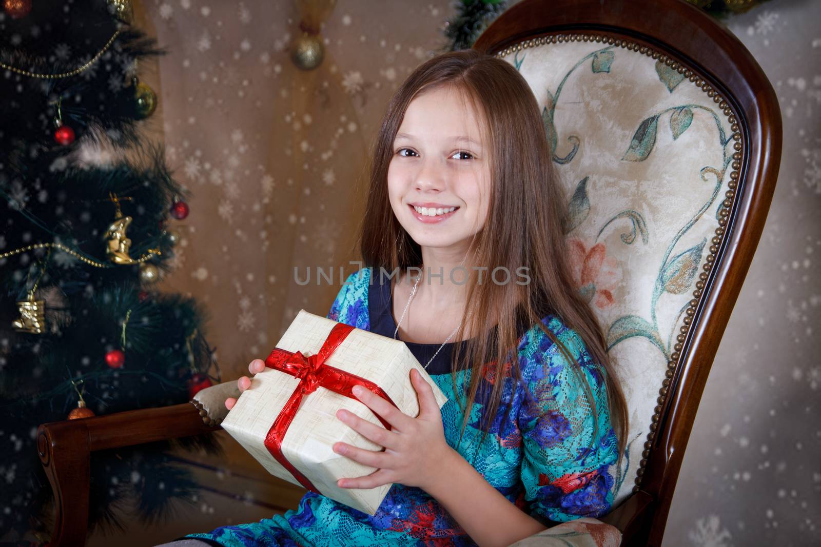 Smiling girl with gift box under Christmas tree