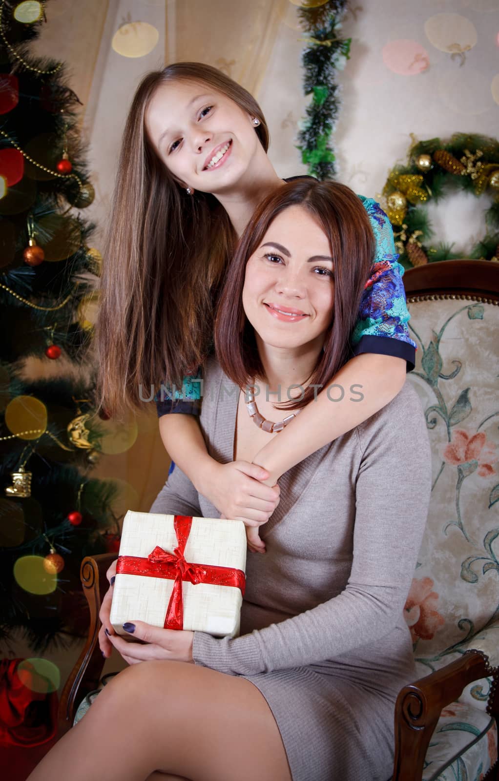 Mother and daughter hugging under Christmas tree 