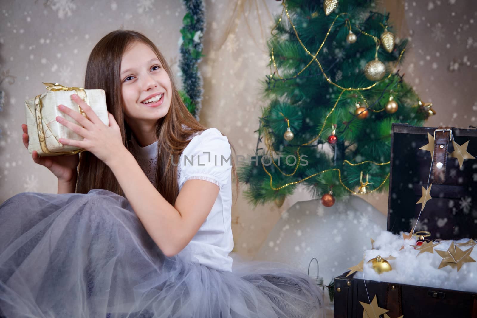 Pretty girl holding gift box under Christmas tree