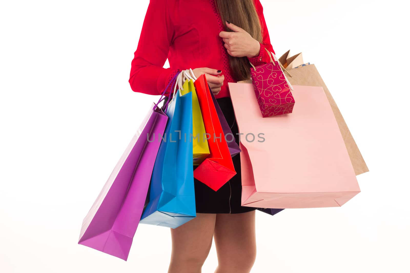 Woman holds her purchases, many colorful paper bags, packages, in her arms after shopping